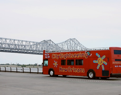 Tourists enjoying the City Sightseeing 1-Day Hop-On Hop-Off Bus Tour in New Orleans, passing by iconic landmarks