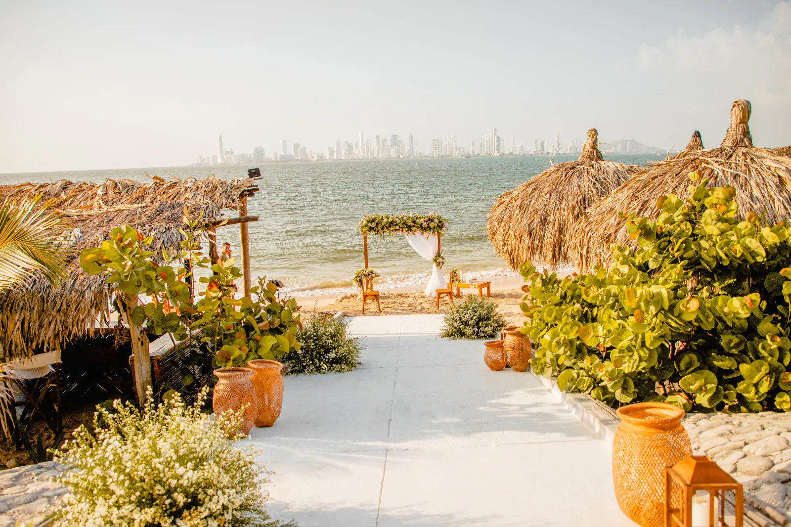 Beachfront setup with thatched huts and floral arch, Rosario Islands, Cartagena.