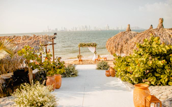 Beachfront setup with thatched huts and floral arch, Rosario Islands, Cartagena.
