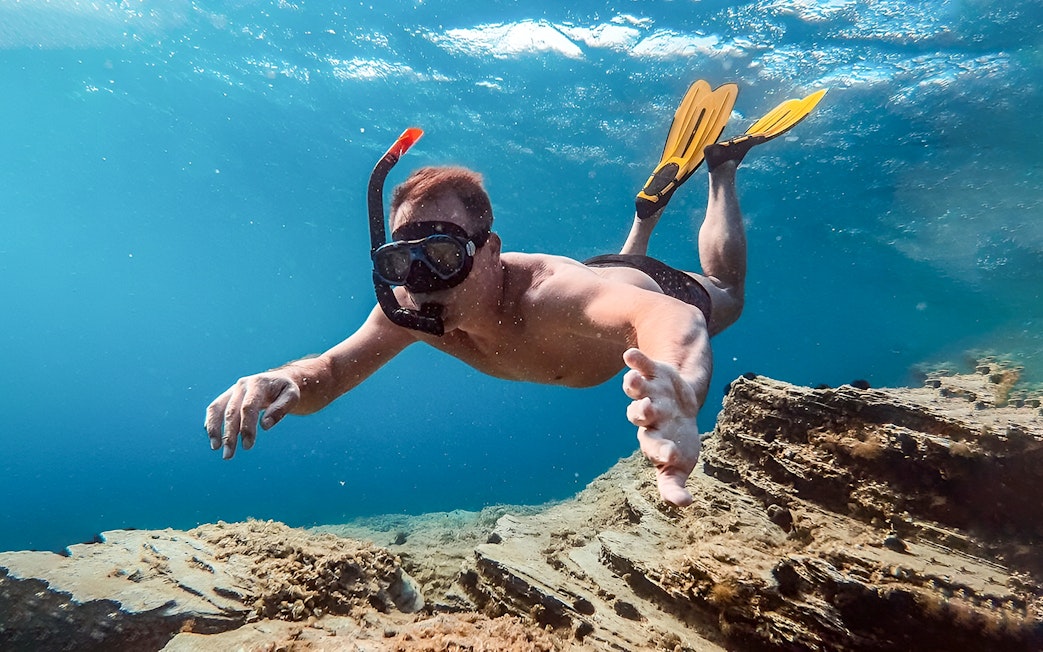 Snorkeler exploring underwater scenery during Santorini Catamaran Cruise.