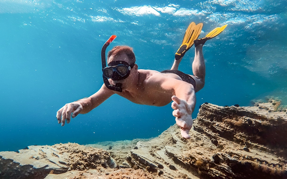 Snorkeler exploring underwater scenery during Santorini Catamaran Cruise.