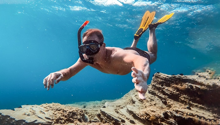 Snorkeler exploring underwater scenery during Santorini Catamaran Cruise.