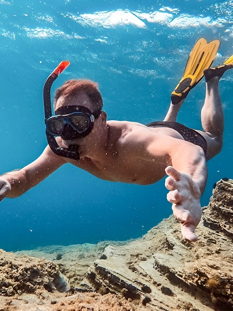 Snorkeler exploring underwater scenery during Santorini Catamaran Cruise.