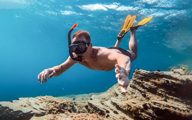 Snorkeler exploring underwater scenery during Santorini Catamaran Cruise.