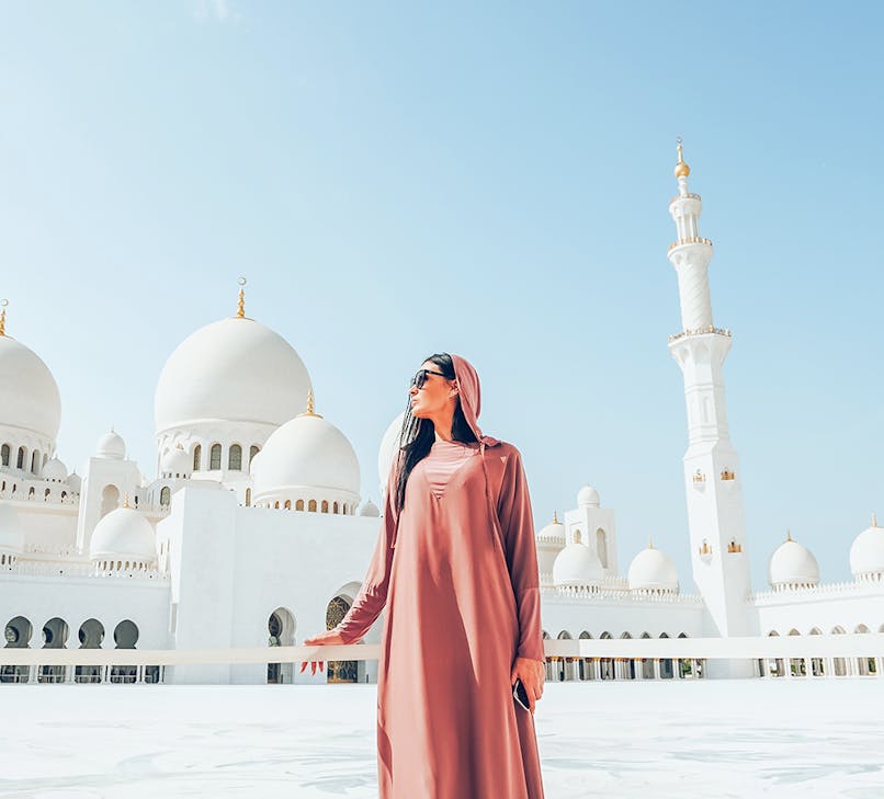 Sheikh Zayed Grand Mosque in Abu Dhabi with tourists exploring the courtyard.