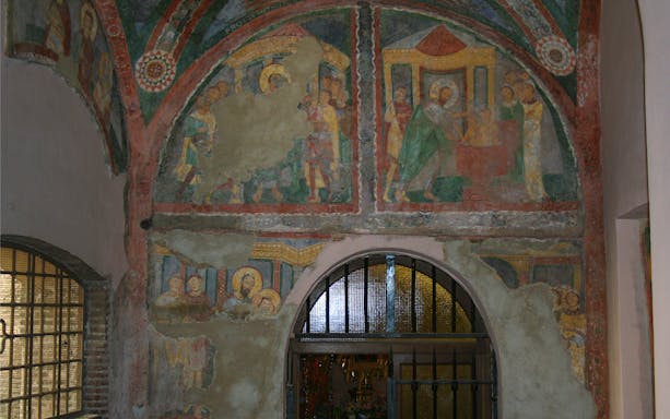 Frescoes inside Basilica of Santa Pudenziana, depicting religious scenes above an arched doorway.