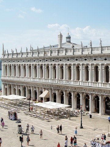 Marciana Library exterior with statues and outdoor seating in Venice, Italy.
