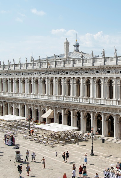 Marciana Library exterior with statues and outdoor seating in Venice, Italy.