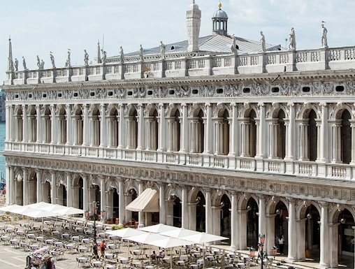 Marciana Library exterior with statues and outdoor seating in Venice, Italy.