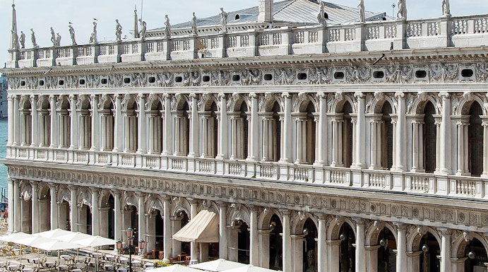 Marciana Library exterior with statues and outdoor seating in Venice, Italy.