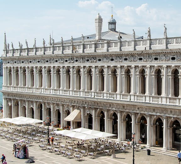 Marciana Library exterior with statues and outdoor seating in Venice, Italy.