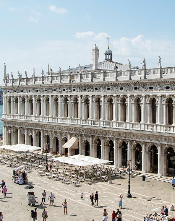 Marciana Library exterior with statues and outdoor seating in Venice, Italy.