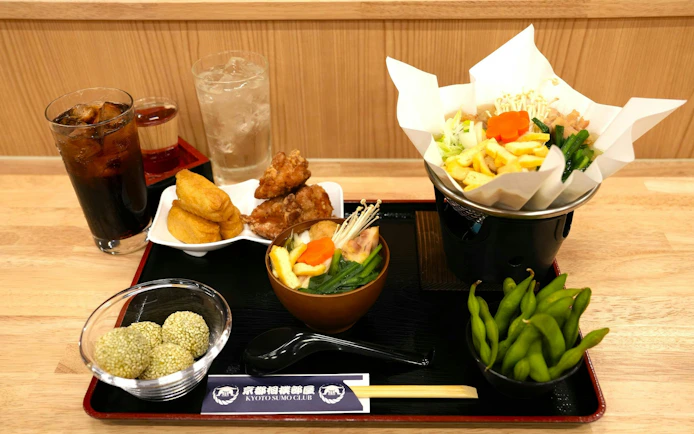 Food platter at Kyoto Sumo Entertainment Show featuring chicken hot pot, edamame, and drinks.