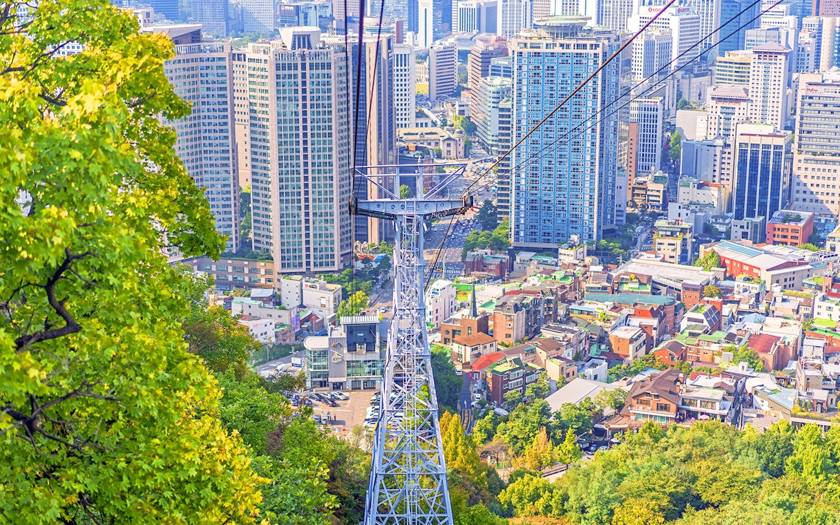 Aerial view of cable car over Namsan with Seoul cityscape.