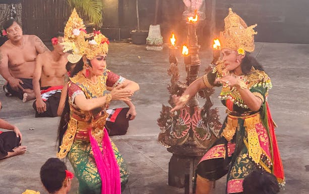 Two dancers in golden headdresses perform Kecak dance at Tanah Lot, Bali.