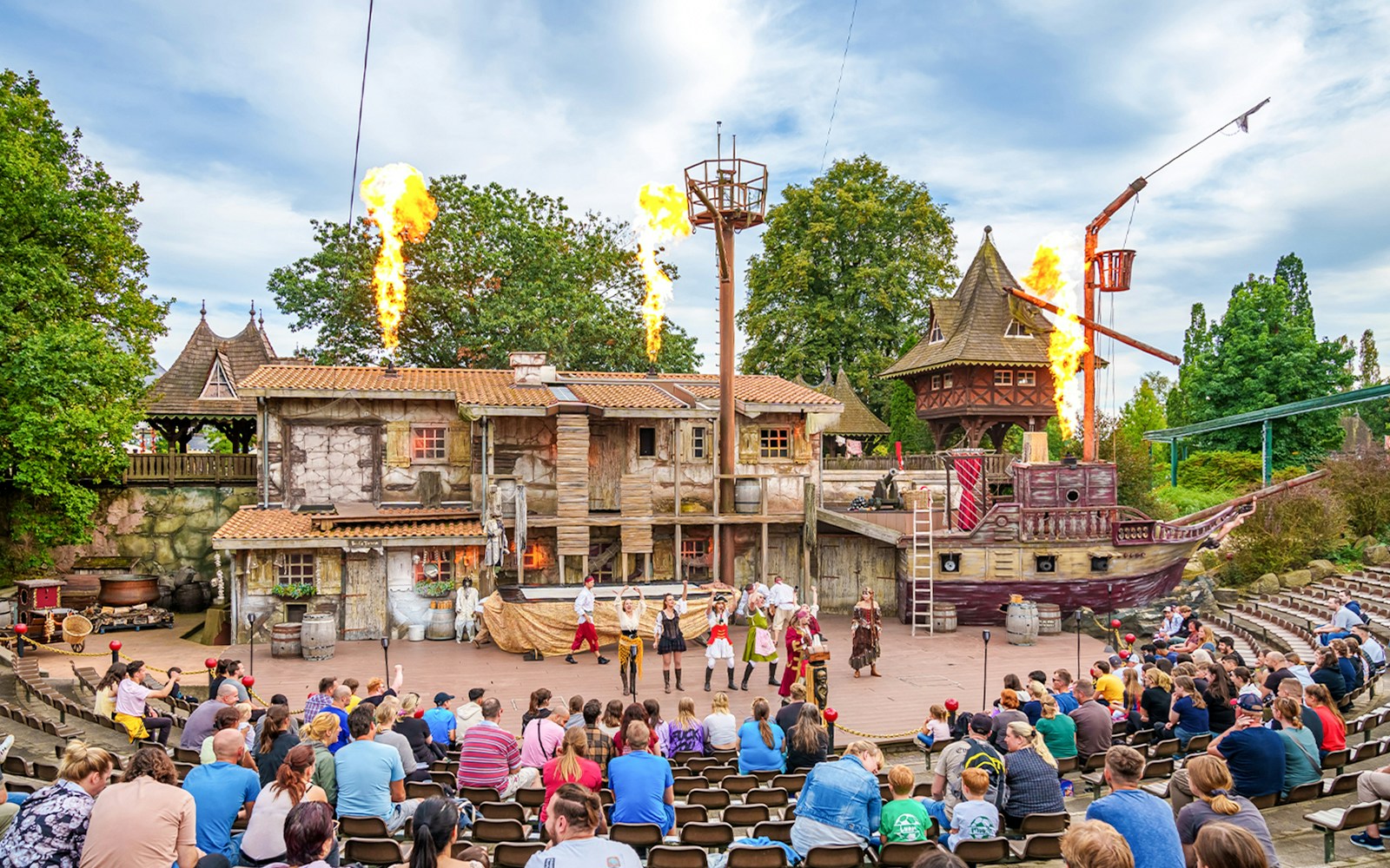 Guests watching Pirate Show at Heide Park Resort, Hamburg with performers on stage and ship backdrop.