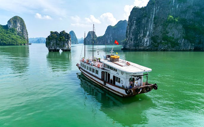 Cruise boat sailing through limestone karsts in Ha Long Bay, Vietnam.
