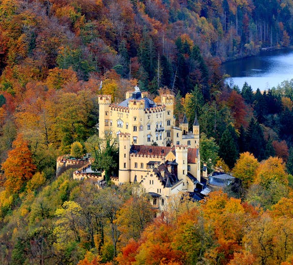 Hohenschwangau Castle surrounded by autumn foliage in Bavaria, Germany.