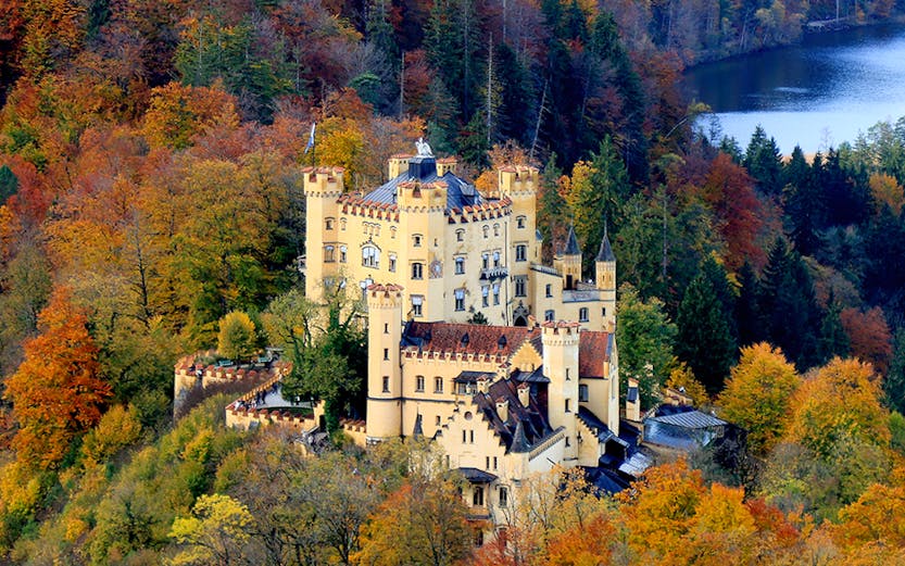 Hohenschwangau Castle surrounded by autumn foliage in Bavaria, Germany.
