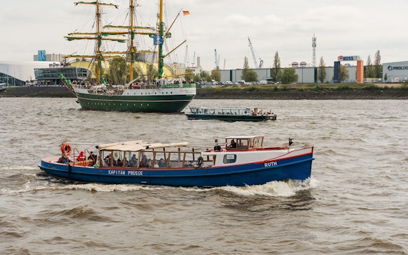 Boat tour on the Elbe River in Hamburg with a sailing ship in the background.