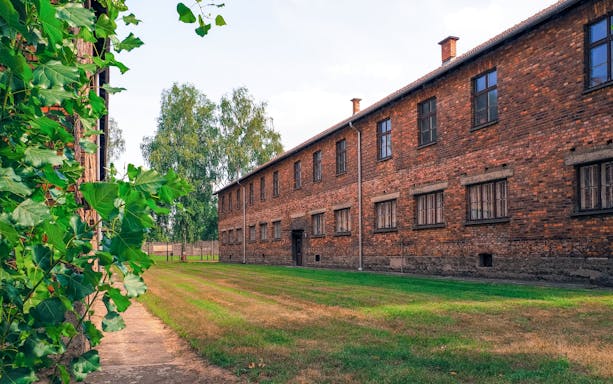 Auschwitz Block 10 brick building with green lawn and trees in the background.