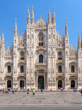 Duomo Milan Cathedral facade with tourists in the square.
