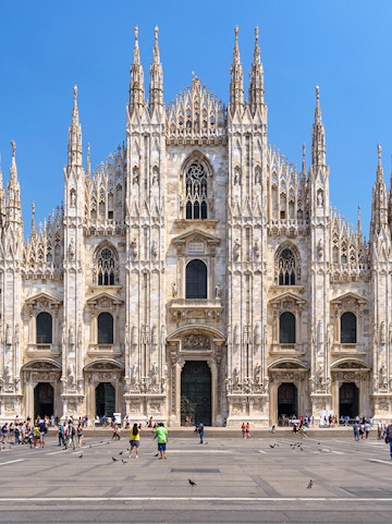 Duomo Milan Cathedral facade with tourists in the square.