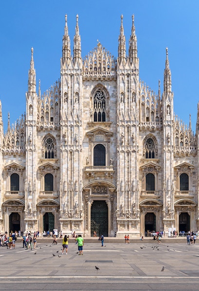 Duomo Milan Cathedral facade with tourists in the square.