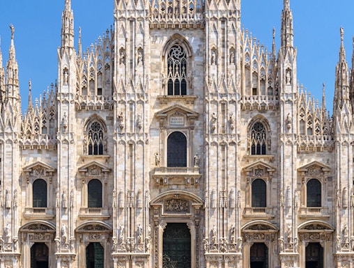 Duomo Milan Cathedral facade with tourists in the square.