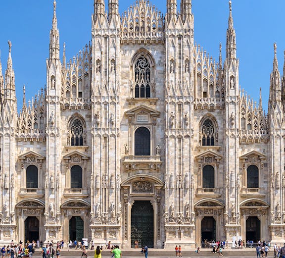 Duomo Milan Cathedral facade with tourists in the square.