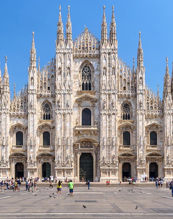 Duomo Milan Cathedral facade with tourists in the square.