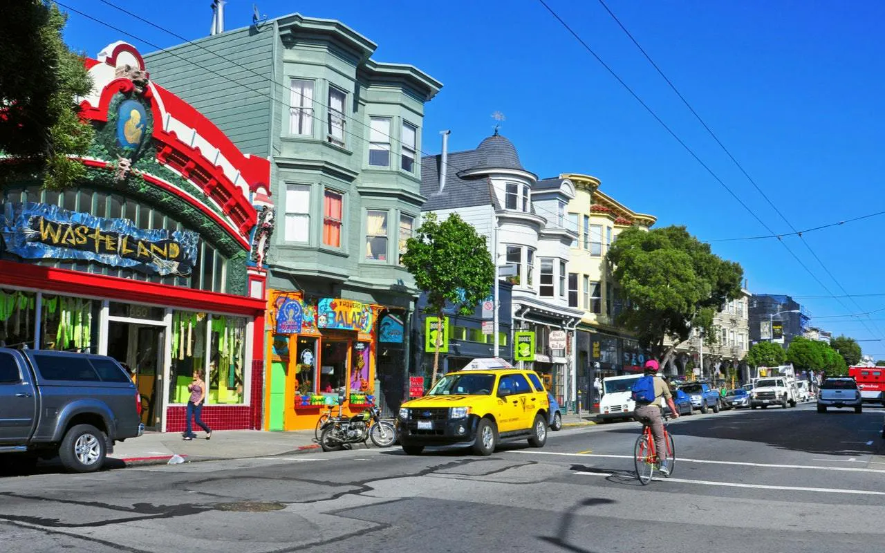 Colorful storefronts and street scene in Haight Ashbury, San Francisco, with cyclist and taxi.
