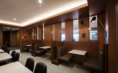 Seating area inside Plaza Premium Lounge with wooden decor and marble tables.