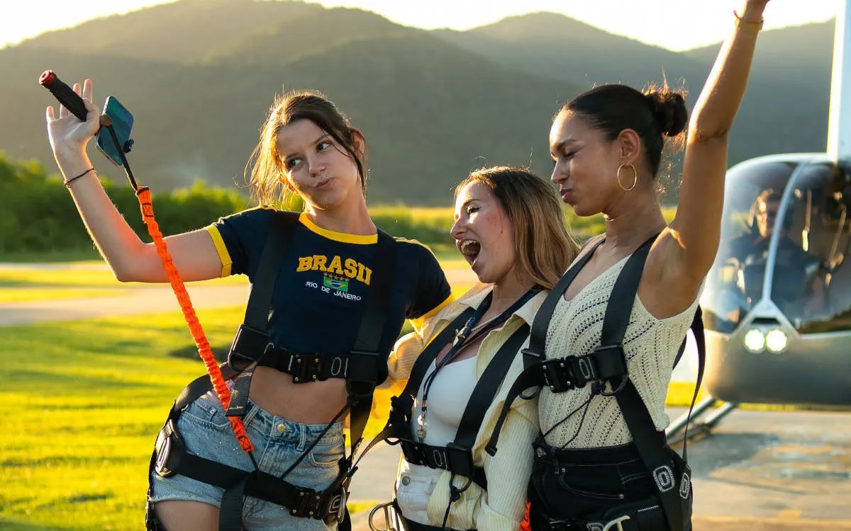 Tourists in harnesses taking a selfie before boarding a helicopter for a Rio de Janeiro tour.