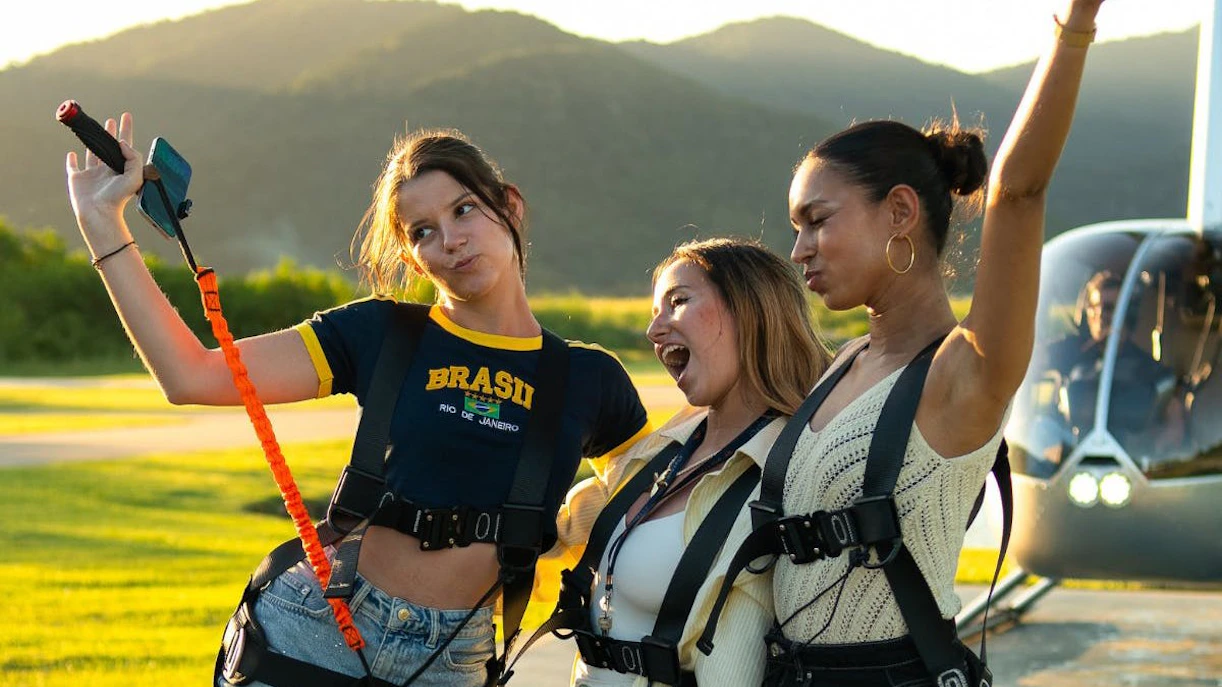 Tourists in harnesses taking a selfie before boarding a helicopter for a Rio de Janeiro tour.