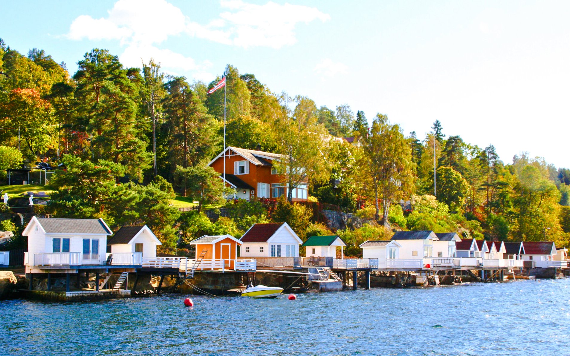Summer cottages along Oslofjord shoreline with lush greenery and clear blue water.