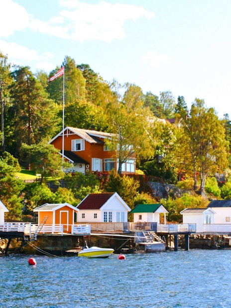 Summer cottages along Oslofjord shoreline with lush greenery and clear blue water.