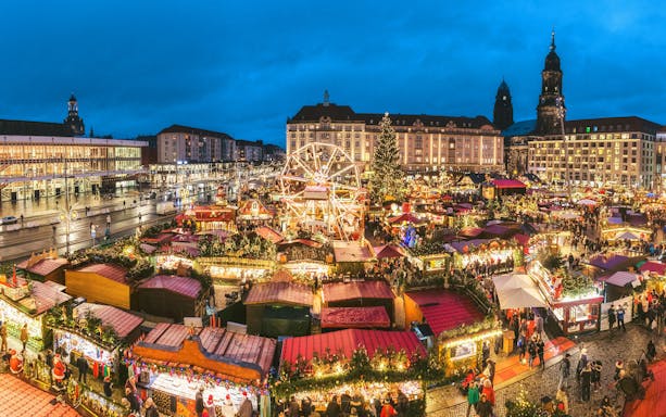 Dresden Christmas market with festive stalls and Ferris wheel at night.
