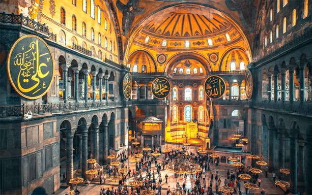 Interior view of Hagia Sophia with visitors exploring the historic architecture in Istanbul.