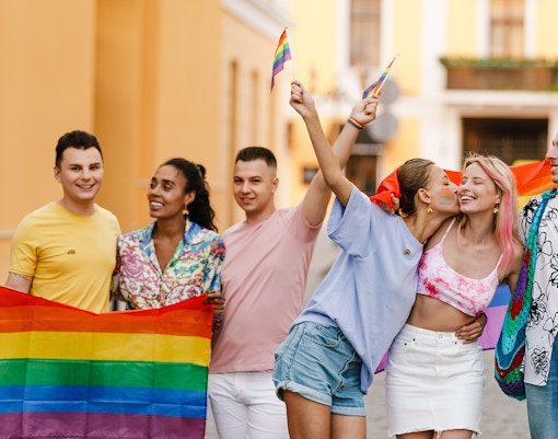 Participants celebrating at the Pride Parade in Barcelona with colorful flags and vibrant costumes.