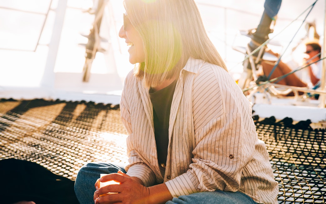 Tourist relaxing on a boat in Lanzarote at sunset with a drink.