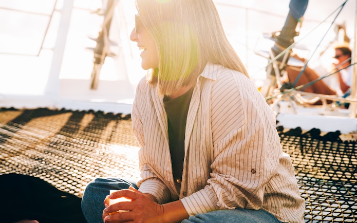 Tourist relaxing on a boat in Lanzarote at sunset with a drink.