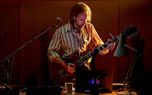 Musician playing guitar on stage during Kenrex performance.