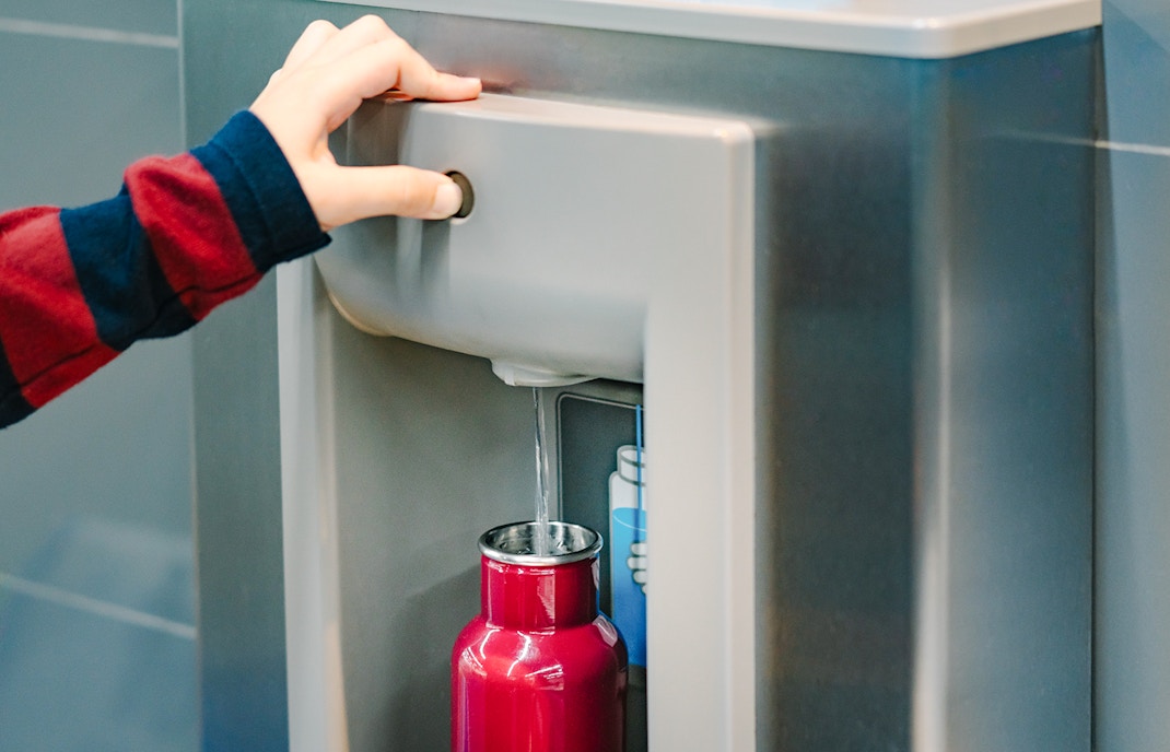 Filling a red bottle at water refill station.