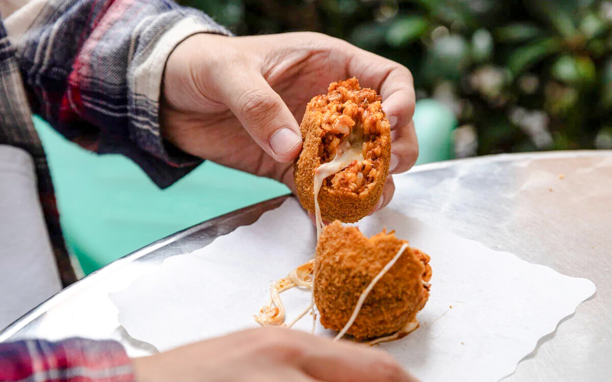 Person enjoying Suppli on a Rome food tour.