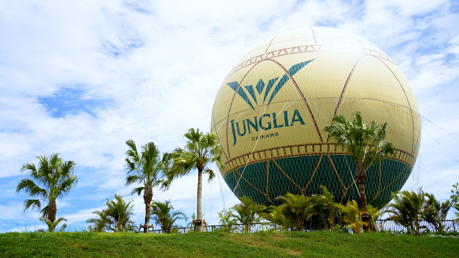 Hot air balloon at JUNGLIA OKINAWA Park surrounded by palm trees.