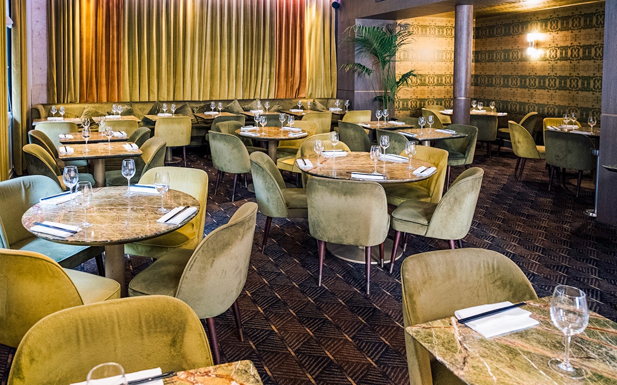 Elegant dining area set for Crazy Horse Paris Show and Dinner with round tables and plush chairs.