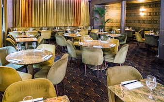 Elegant dining area set for Crazy Horse Paris Show and Dinner with round tables and plush chairs.