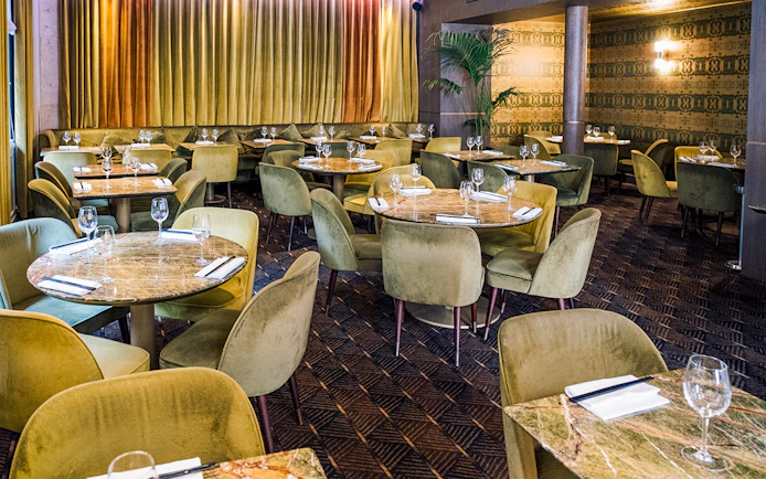 Elegant dining area set for Crazy Horse Paris Show and Dinner with round tables and plush chairs.