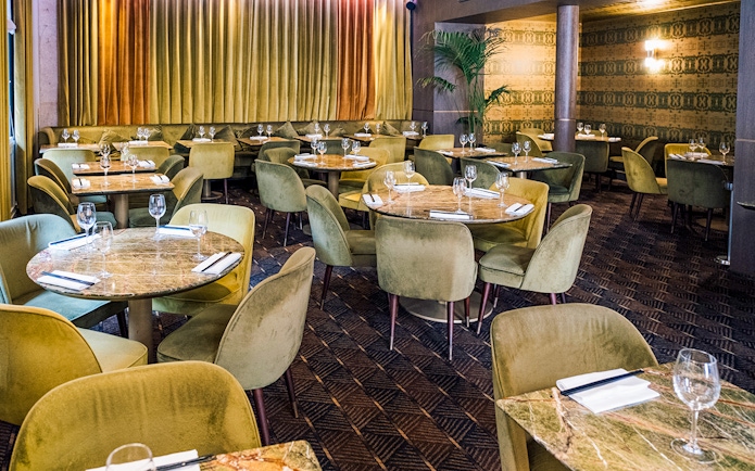 Elegant dining area set for Crazy Horse Paris Show and Dinner with round tables and plush chairs.